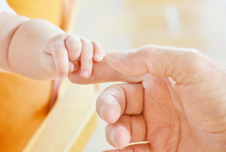 Newborn baby holding a parent's finger