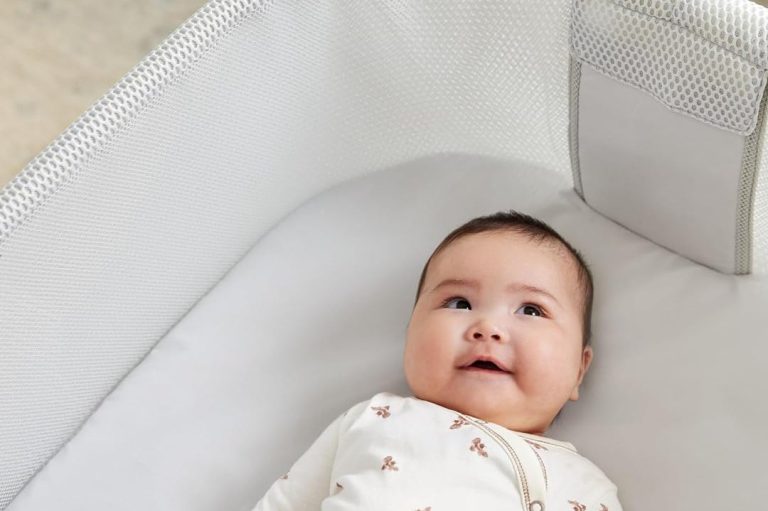 Awake, smiling baby lying on their back in a bassinet