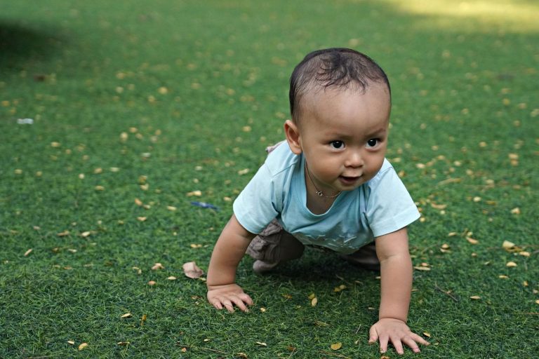 Baby crawling on green grass