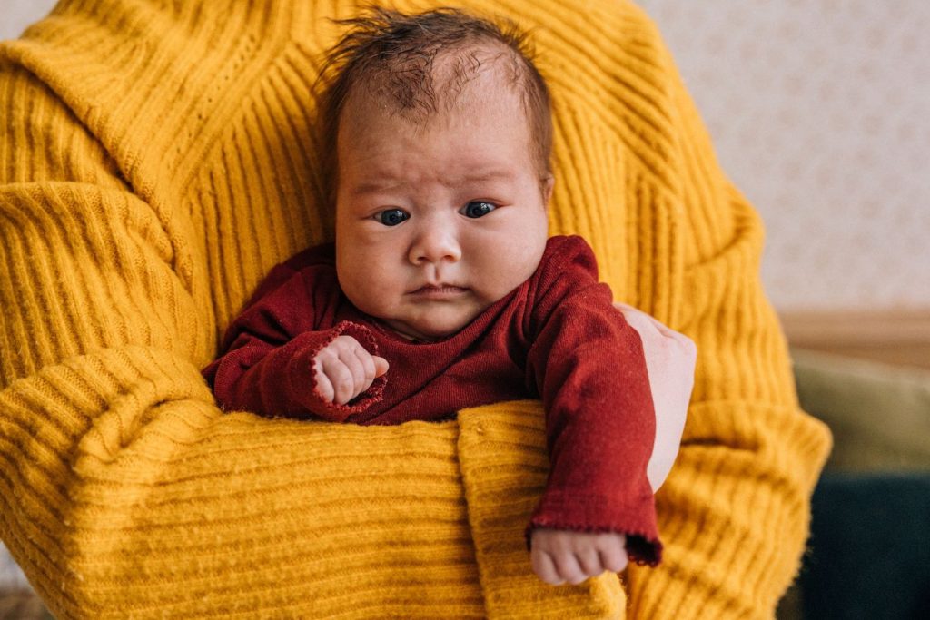 Parent holding a baby upright against their chest