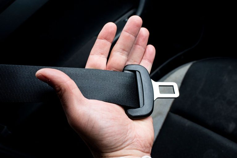 Hand holding a car seat belt buckle
