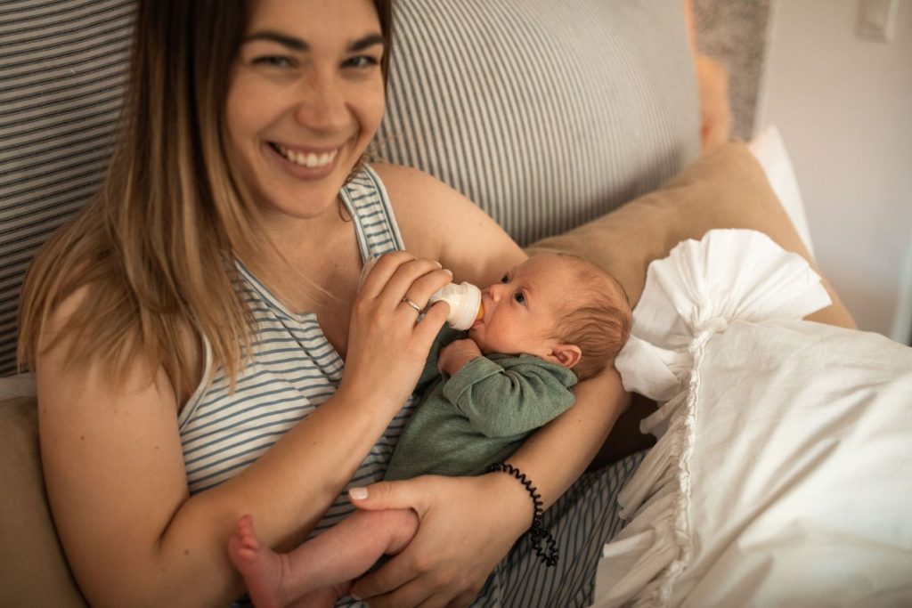 Smiling mother bottle-feeding her baby
