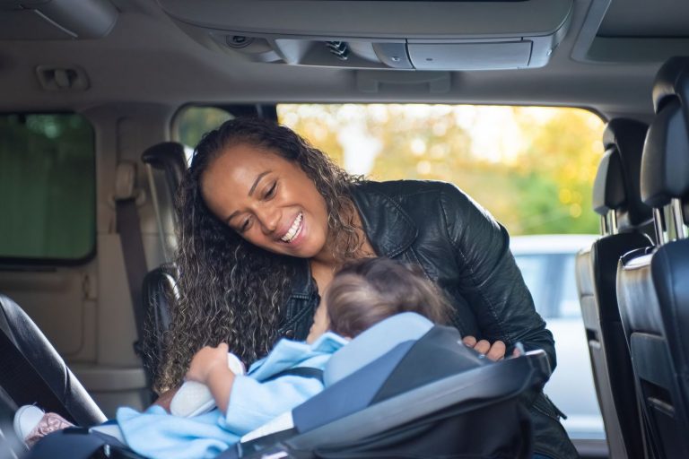 Mother checking on her baby in a rear-facing infant car seat