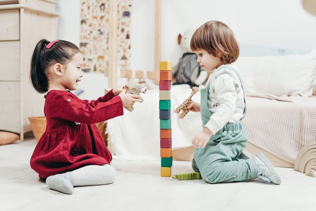 Two young children building with toy blocks