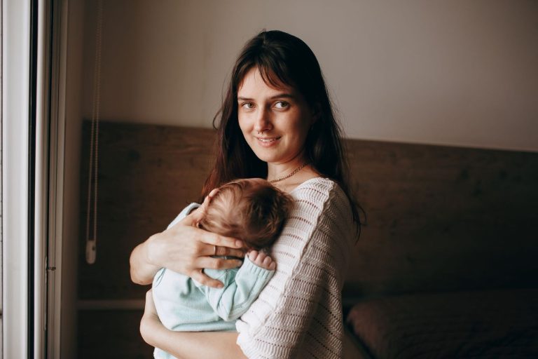 Mother holding her baby close by a window